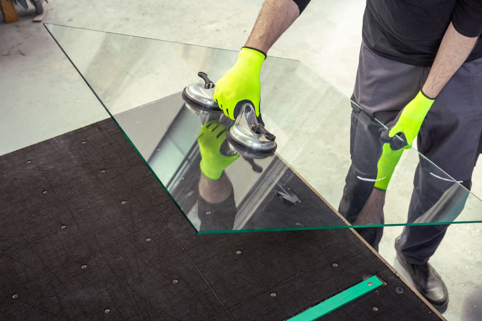 A glazier lifts the glass in the factory using a special glass suction cup.